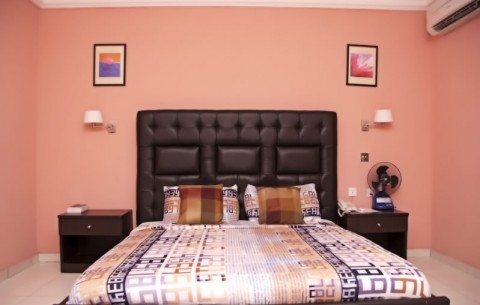 A bedroom with light pink walls and a bed with two wooden side tables.